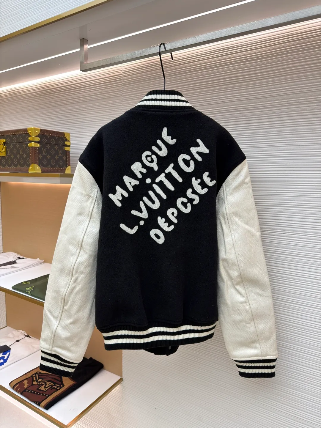 LOUIS VUITTON checkerboard embossed genuine leather and wool baseball jersey ●Original version: 51000 purchased and developed ●Item number: 1680926-i15 ●Fabric: genuine leather wool fabric ●Technology: embroidery ●Version: fitted version ●Weight: about 1770 grams ●Size: 44-46-48-50 ●Description: The fabric is made of 80% wool, with a weight of 750g. It is made of newly sheared wool and is dyed in reactive black in the vat. The colored cloth is bristle process. After brushing 5 times and washing 6 times, the fluffy surface fluff is trimmed flat, and the surface of the fabric appears fluffy. It has a hollow three-dimensional fluffy effect. You can feel the elasticity of the fabric when you touch and press it with your hands. The newly sheared wool yarn is long-fiber and is not easy to pill after shearing. The front and back panels are embroidered with Tajima embroidery machines imported from Japan. The nylon material is super matte and the tatami stitch method is multi-layered. Overlapping thread embroidery, the front chapter is made of viscose yarn, three-dimensional toothbrush embroidery, the mold is opened to determine the pile height and the suede is smoothed by hand, using acrylic round bubble beads, the surface of the bubble beads is sprayed three times, the base paint is latex paint, and the middle layer is sprayed with pearls Pearl white paint, the outer layer is sprayed with translucent glossy paint, the translucent bright white effect is completely comparable to that of mother-of-pearl. There are a total of 154 beads in the chapter. Each bead is dusted and positioned to ensure that it is flush with the edge of the chapter. The visual effect is not obtrusive. The two sleeves are made of water Made of dyed cowhide. Compared with spray-painted cowhide, there is nothing attached to the surface of water-dyed cowhide. Pure water-based dyes are continuously stirred in the tank to naturally color. During the period, samples are taken to compare the color of the Y-version sleeves according to the degree of coloring. When the colors are basically the same, they can be washed and dried naturally to produce the finished product. The thickness of the finished leather is 12mm. The embossing is made of a large-size aviation aluminum plate material mold. All the flowers are pressed according to the code positioning. An electric hydraulic control system is used, and the constant temperature and timing are automatically operated. The small sleeve logo is embossed separately from the small mold. It is pressed by electromagnetic pulse pressure and heating. After the sleeves are cut and embossed, the leather base is all shoveled to a thickness of 8mm. The leather thickness is reduced and the hand feels softer and closer to the body. The diamond-shaped plaid embossing on the surface causes an anti-skin phenomenon due to the thinning of the leather base. The pattern will naturally increase from the deep base state. Lightened, the diamond check pattern and the leather pebbles form a visually invisible effect. It is matched with cupro + cotton blended lining, the ribs are made of combed cotton yarn, and the horizontal loom imported from Taiwan has inter-color jacquard. It is matched with a custom-made molded aluminum alloy material with a logo spray-painted four-button buckle.